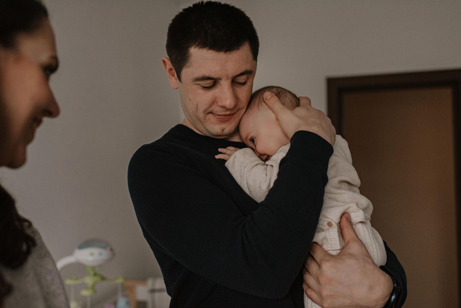 Parent and infant share intimate bonding moment in dimly lit room.
