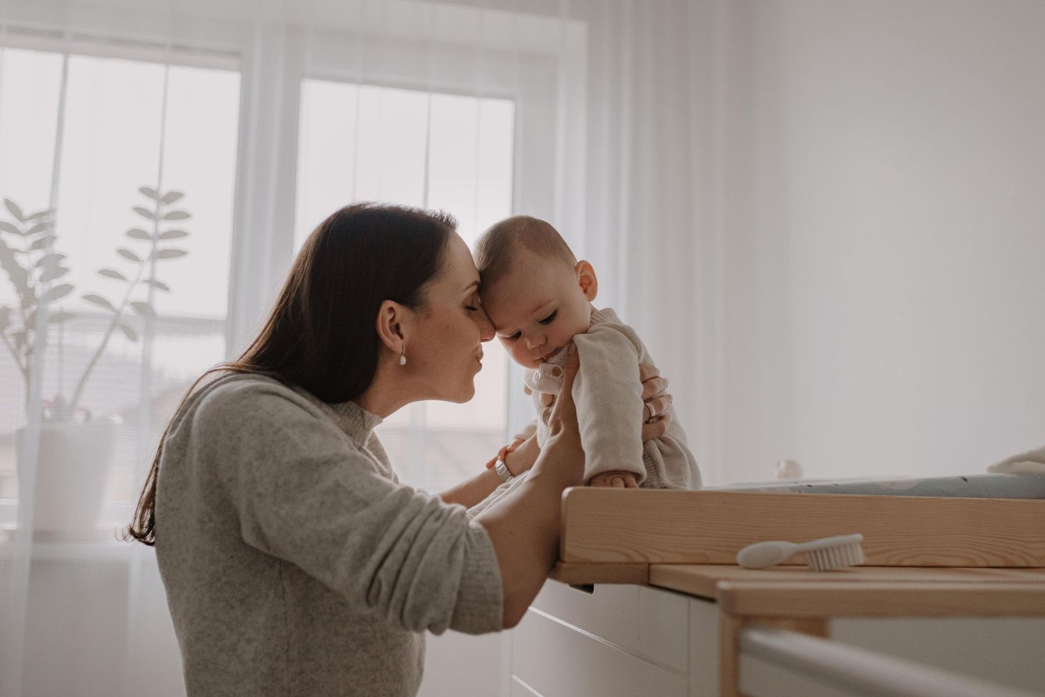 Bright interior scene of parent and baby bonding by window.