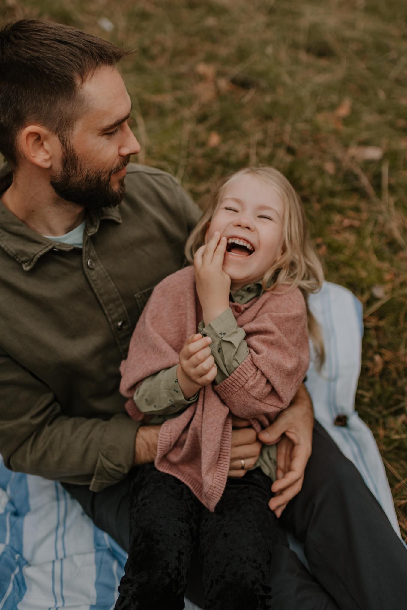 Joyful moment shared between parent and child sitting on blanket outdoors.