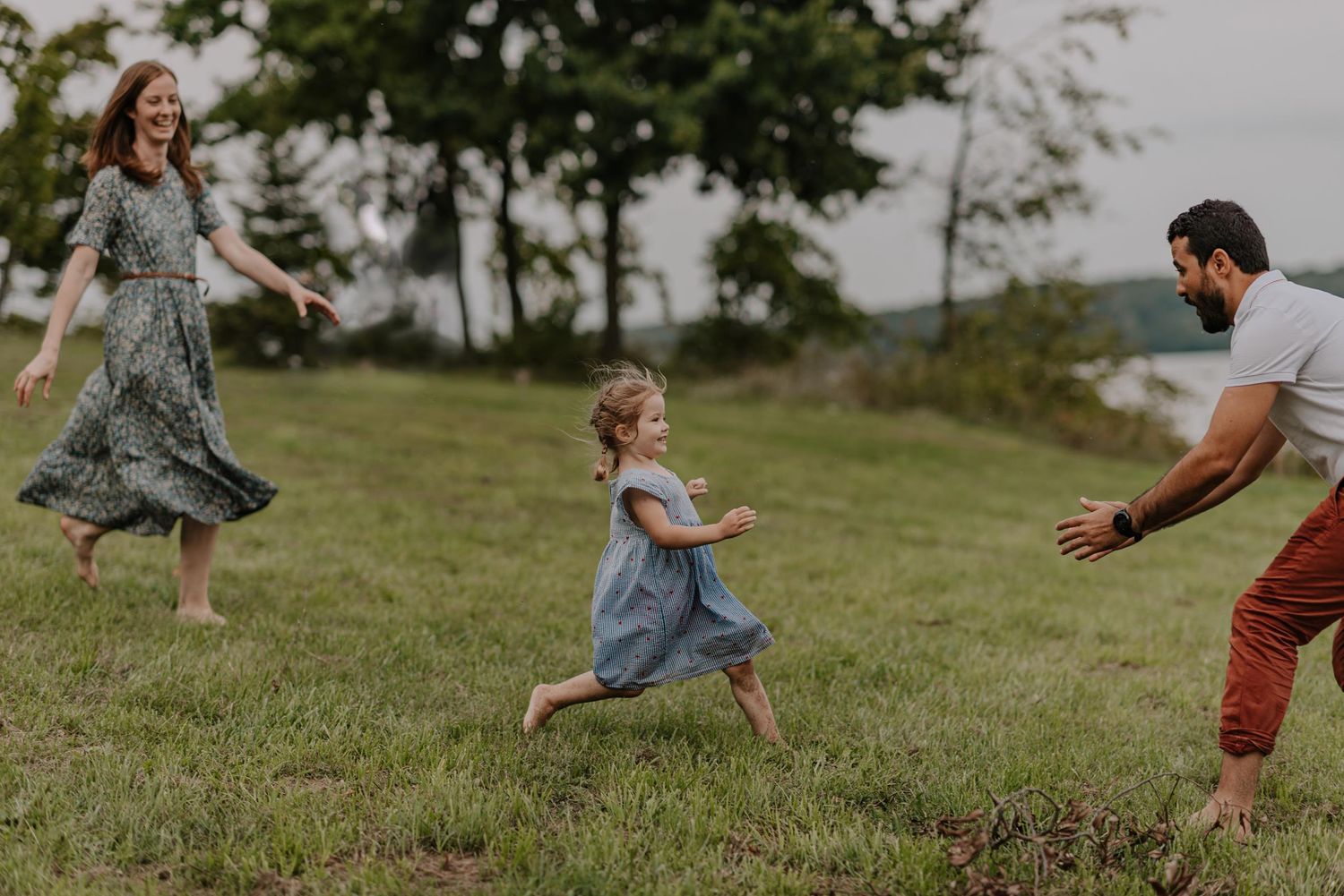 Family playing a fun chasing game together in a grassy field on a summer day.