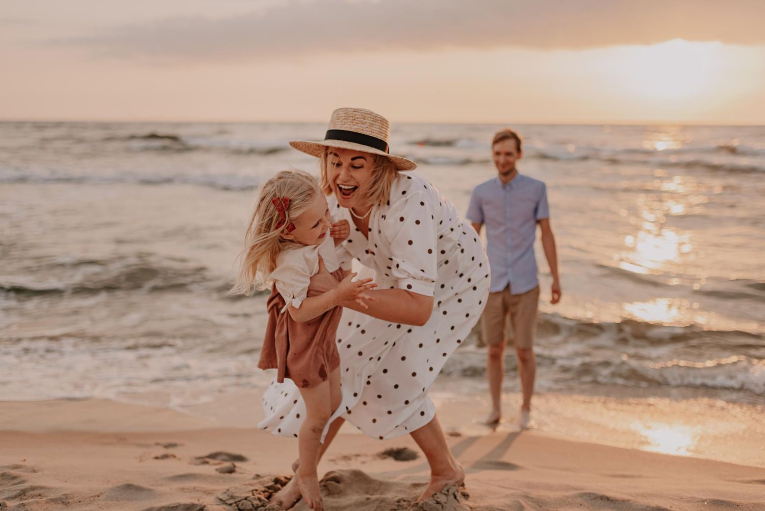 Sweet moment shared on sandy beach with sunset ocean backdrop.