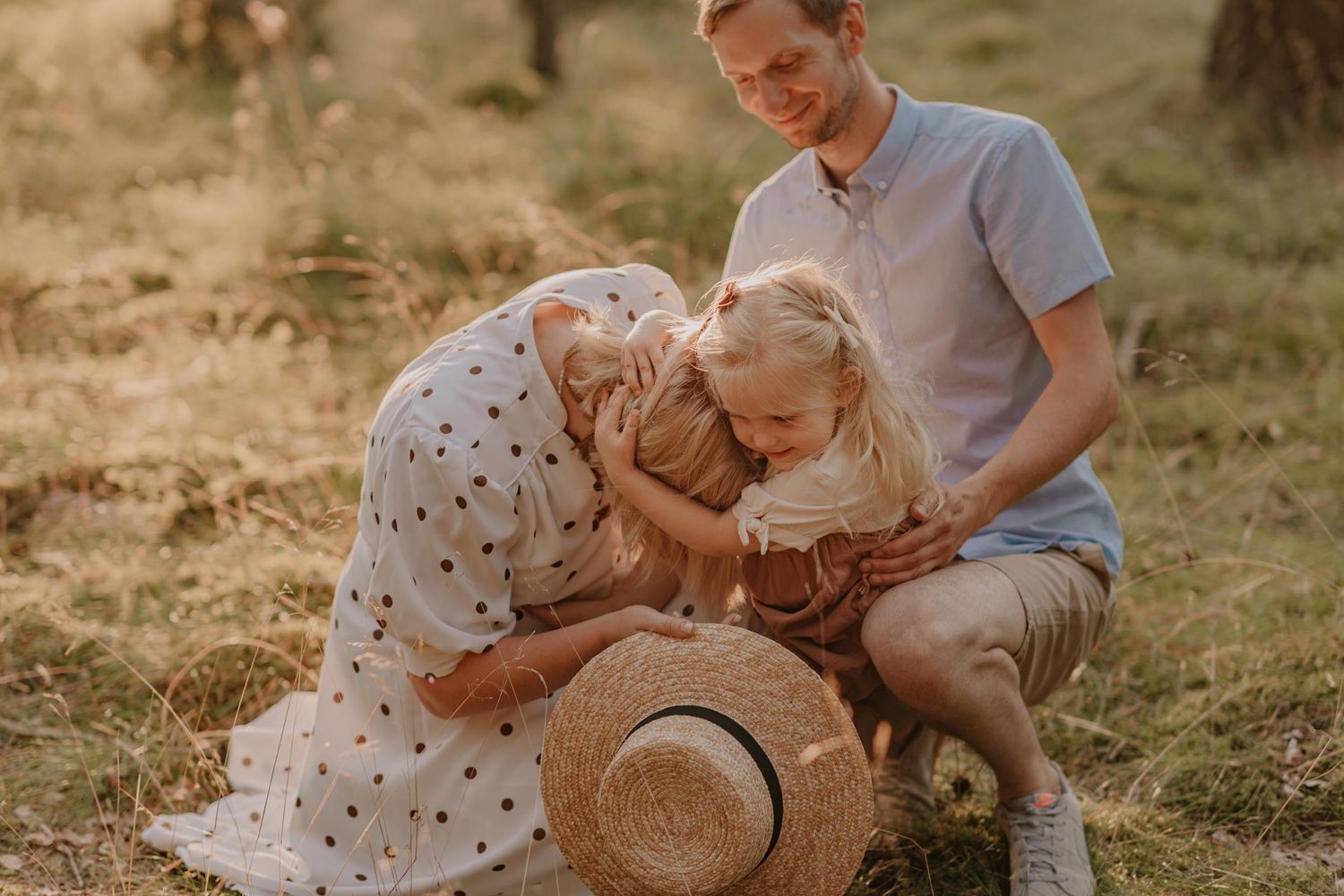 Family enjoying playful moments together on a sunny afternoon in a park setting.