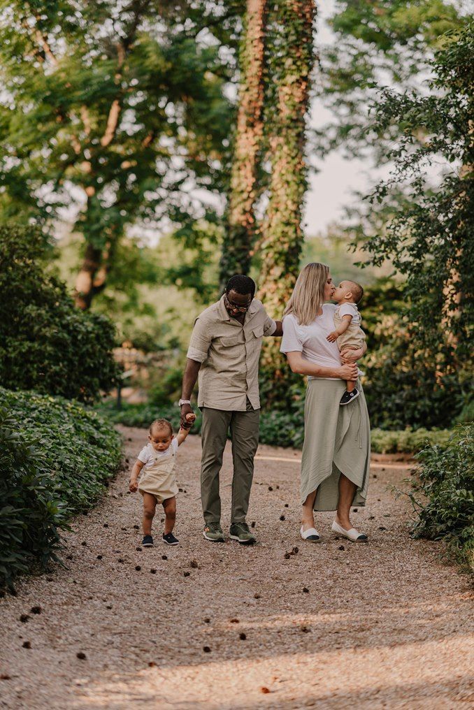 Family enjoying a casual stroll together along a tree-lined garden path.