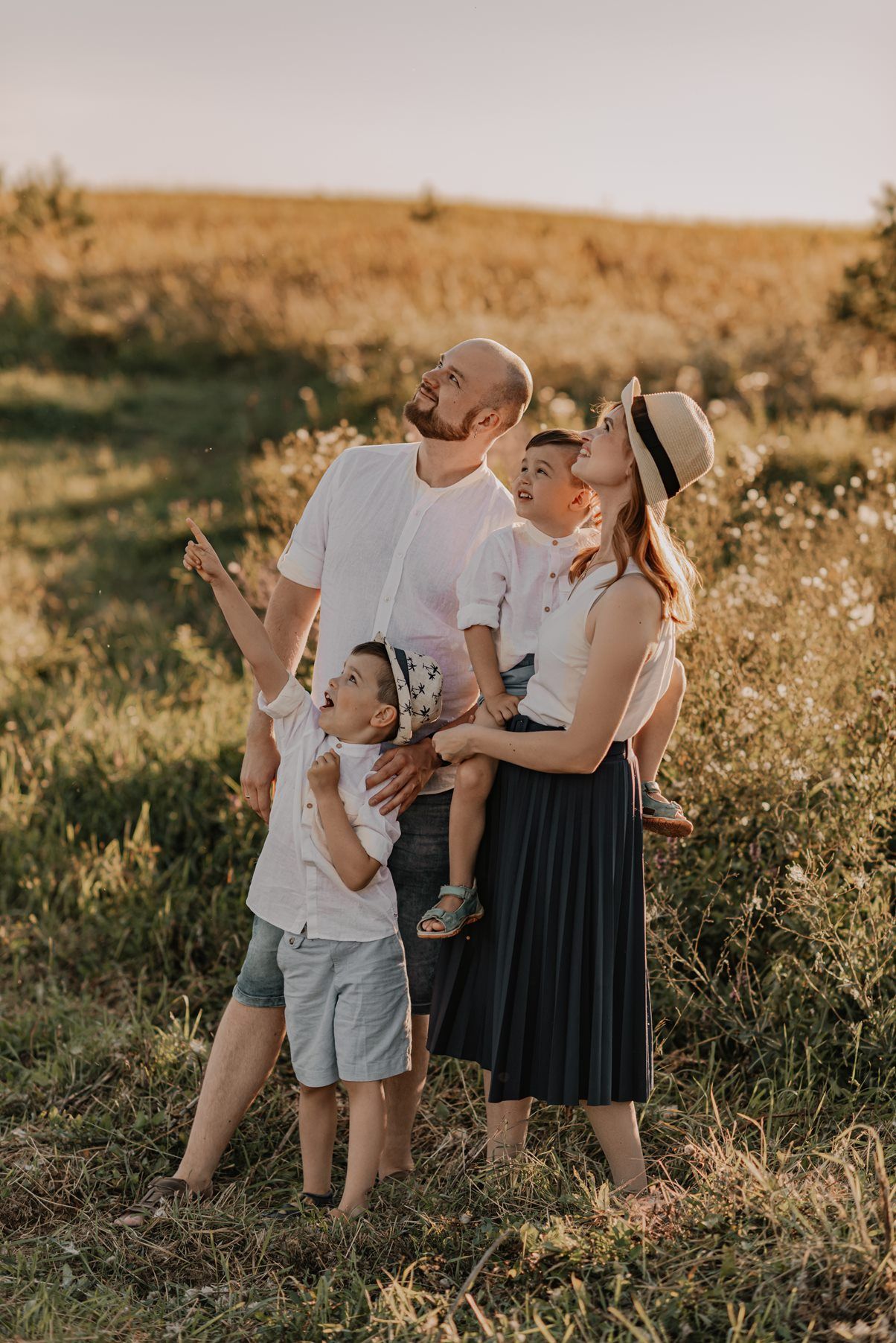 Family enjoying playful moments together in a sun-drenched meadow.