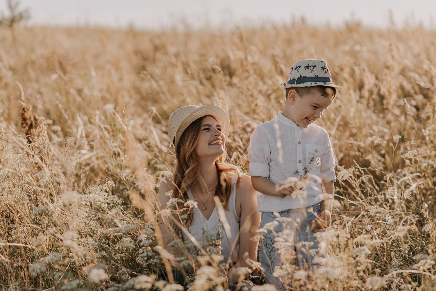 Family interacting naturally in tall grass during golden hour photography session.