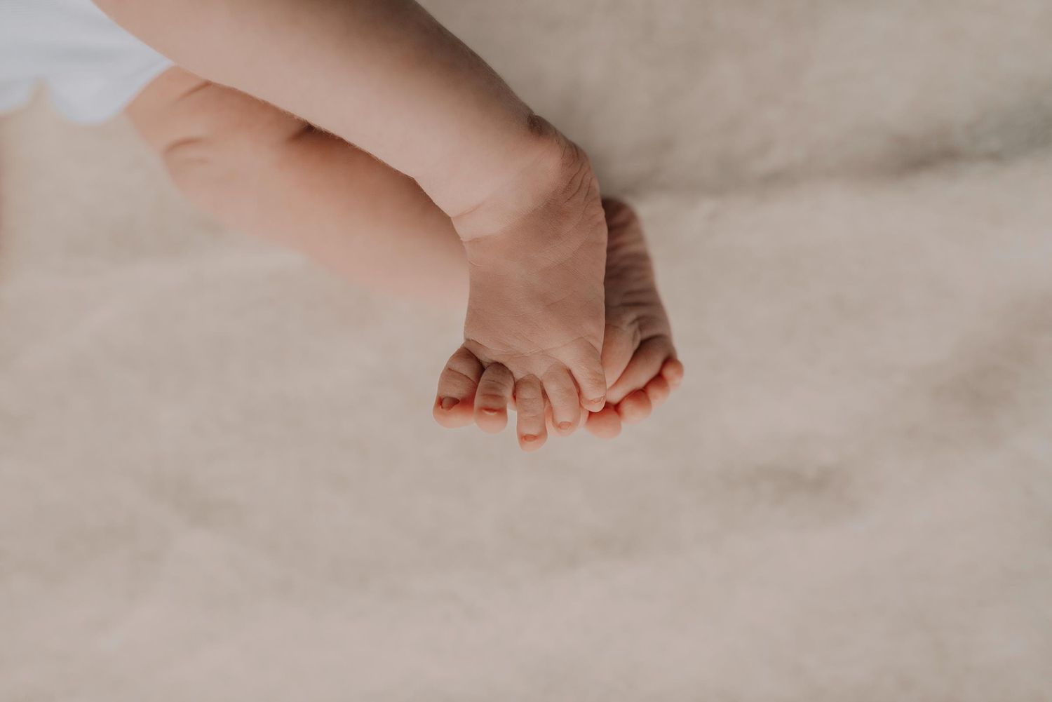 Close up shot of a baby's tiny foot against a white blanket background.