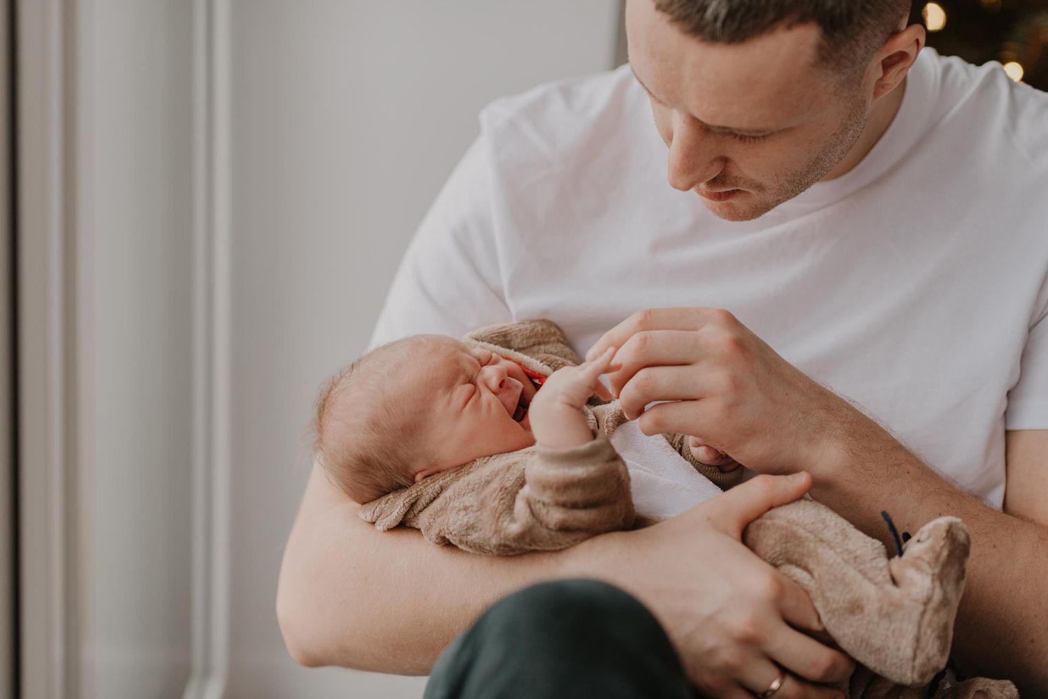 Parent cradling and feeding newborn baby in gentle indoor lighting.