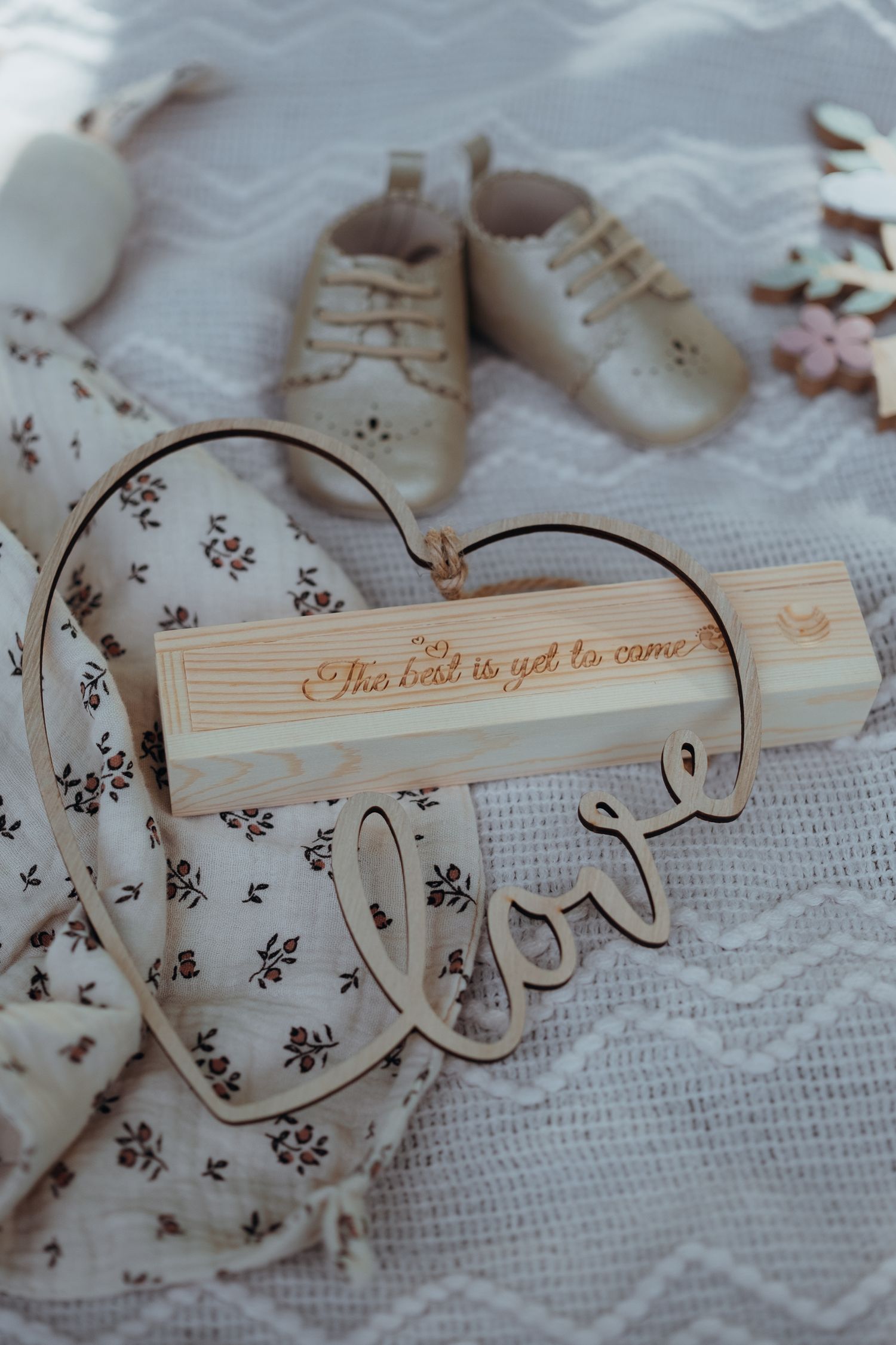 Photo d'une séance famille avec un bébé. On y voit des chaussons de bébé, une boîte d'un test de grossesse et un coeur "love" en bois.