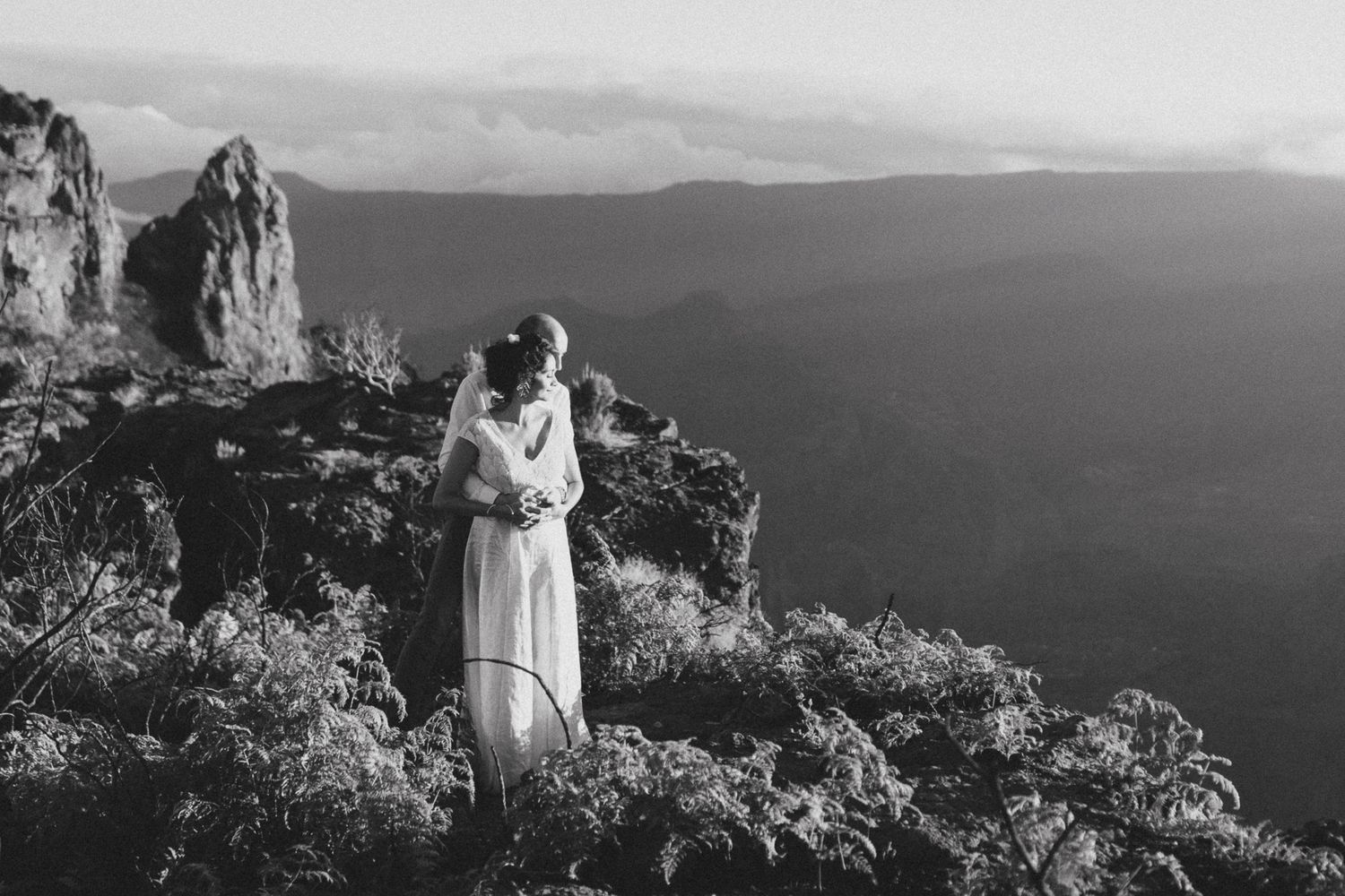 Séance photo de couple en pleine nature, panorama montagneux en arrière-plan.