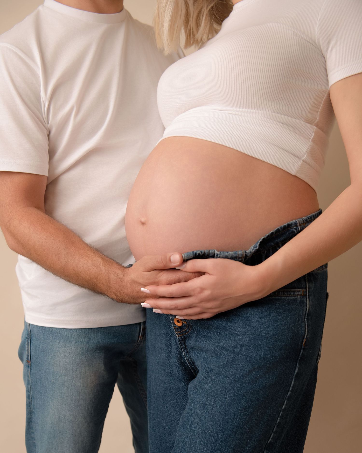 A series of photos showing a pregnant belly growing progressively larger while wearing jeans and a white t-shirt.