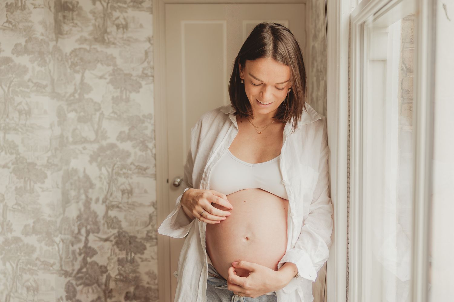Indoor maternity photos featuring a woman in white against exposed brick walls.