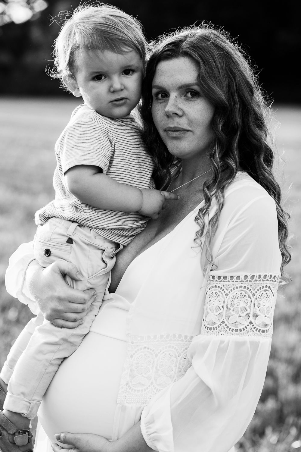 Black and white portrait series showing tender moments between parent and child in matching white lace outfits outdoors.