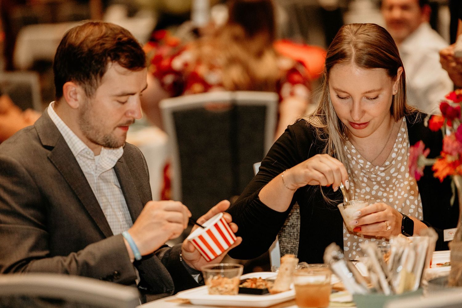People enjoying desserts and treats at a social gathering in warm lighting.