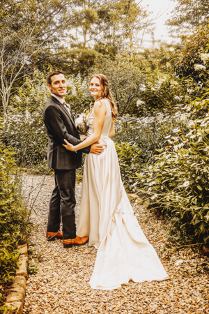 Romantic wedding photos of a couple on a garden path with autumn foliage.