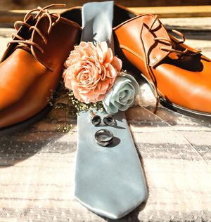 Wedding shoes in orange and blue with delicate floral accents displayed against a rustic background.