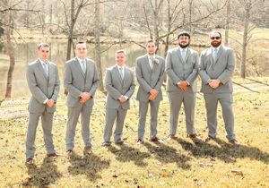 Groomsmen in matching gray suits lined up outdoors during autumn.