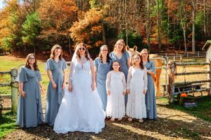 Wedding party posing outdoors with fall foliage and trees in the background.