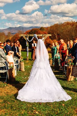 Outdoor wedding ceremony setup with white chairs and mountain backdrop in autumn.