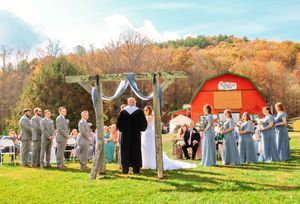 Wedding party stands in line against a backdrop of fall colors and a red barn.