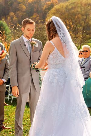 A wedding couple shares a tender moment in a beautiful autumn setting with golden foliage in the background.