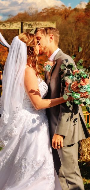 Newlyweds share intimate moments during their fall wedding photoshoot with autumn foliage.