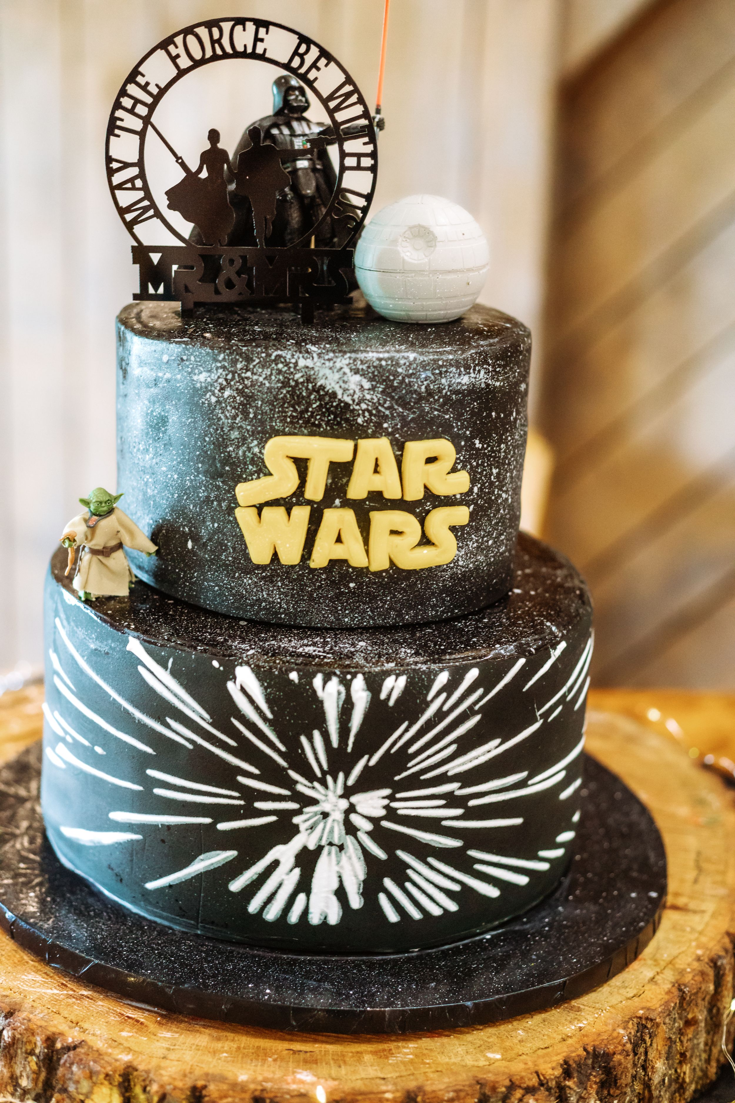 Star Wars themed wedding cake with Death Star topper and hyperspace design on black and blue tiers.