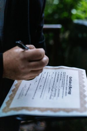 Close-up of hands signing wedding documents during ceremony.