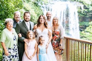 Wedding guests and family members pose together on deck with waterfall vista.