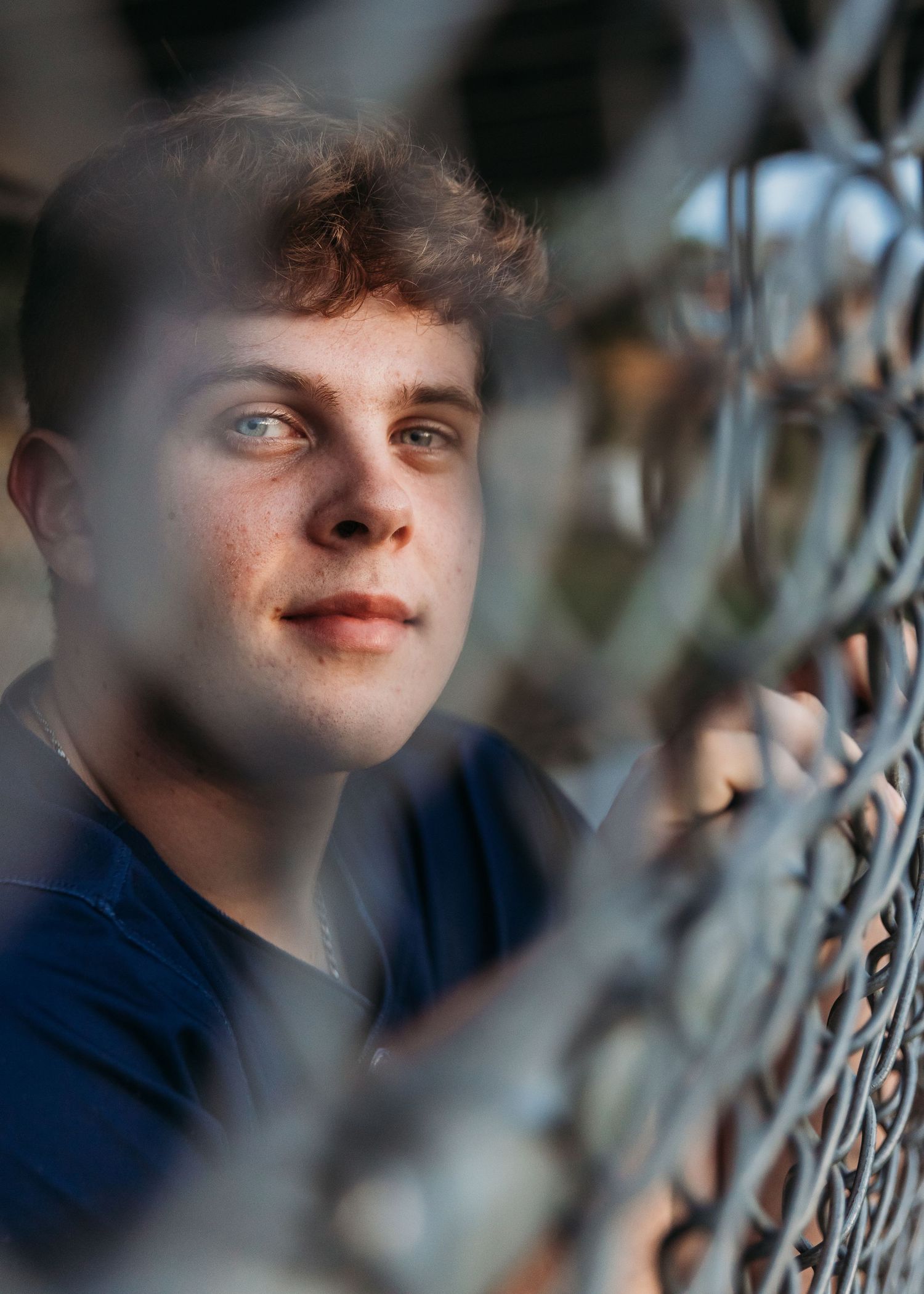 A series of artistic portrait shots through a wire fence with soft bokeh and moody lighting effects.