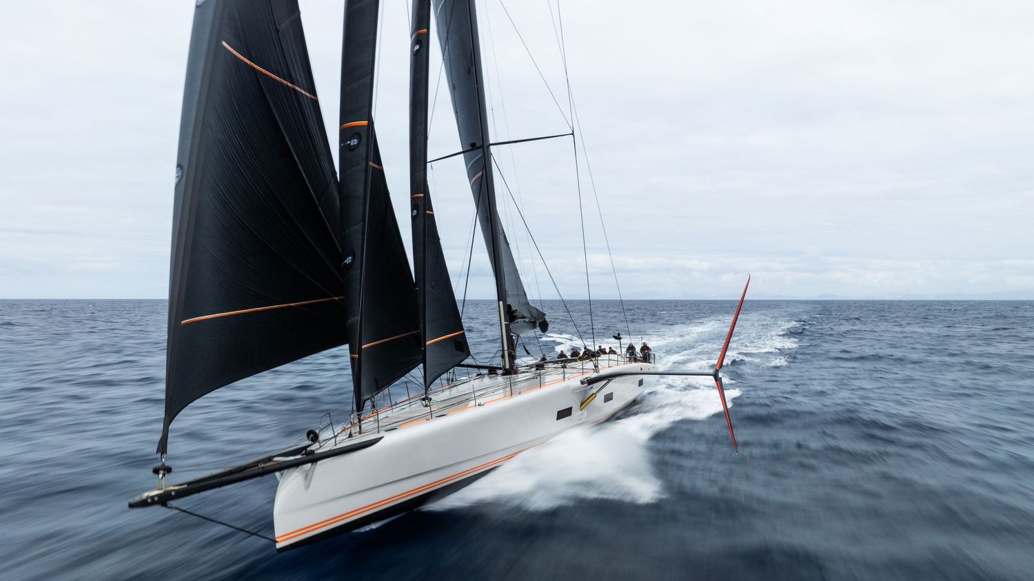 High-performance sailing yacht with black sails gliding across open ocean waters.