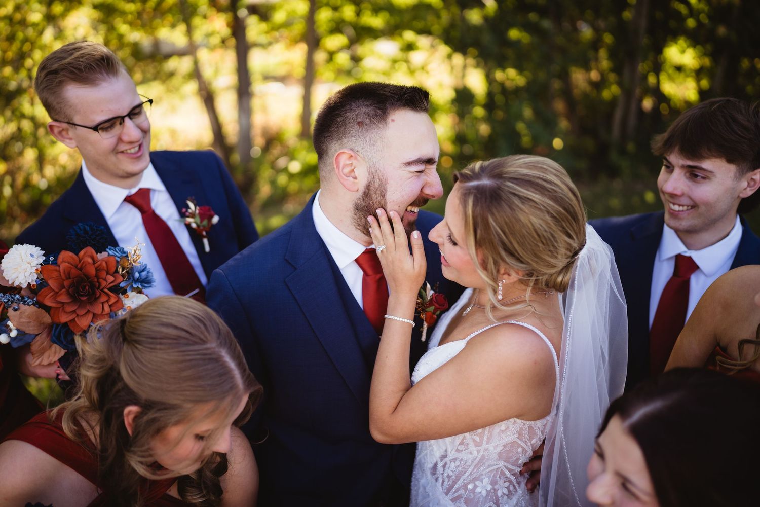 Newlyweds and wedding party share candid moments outdoors during fall celebration.