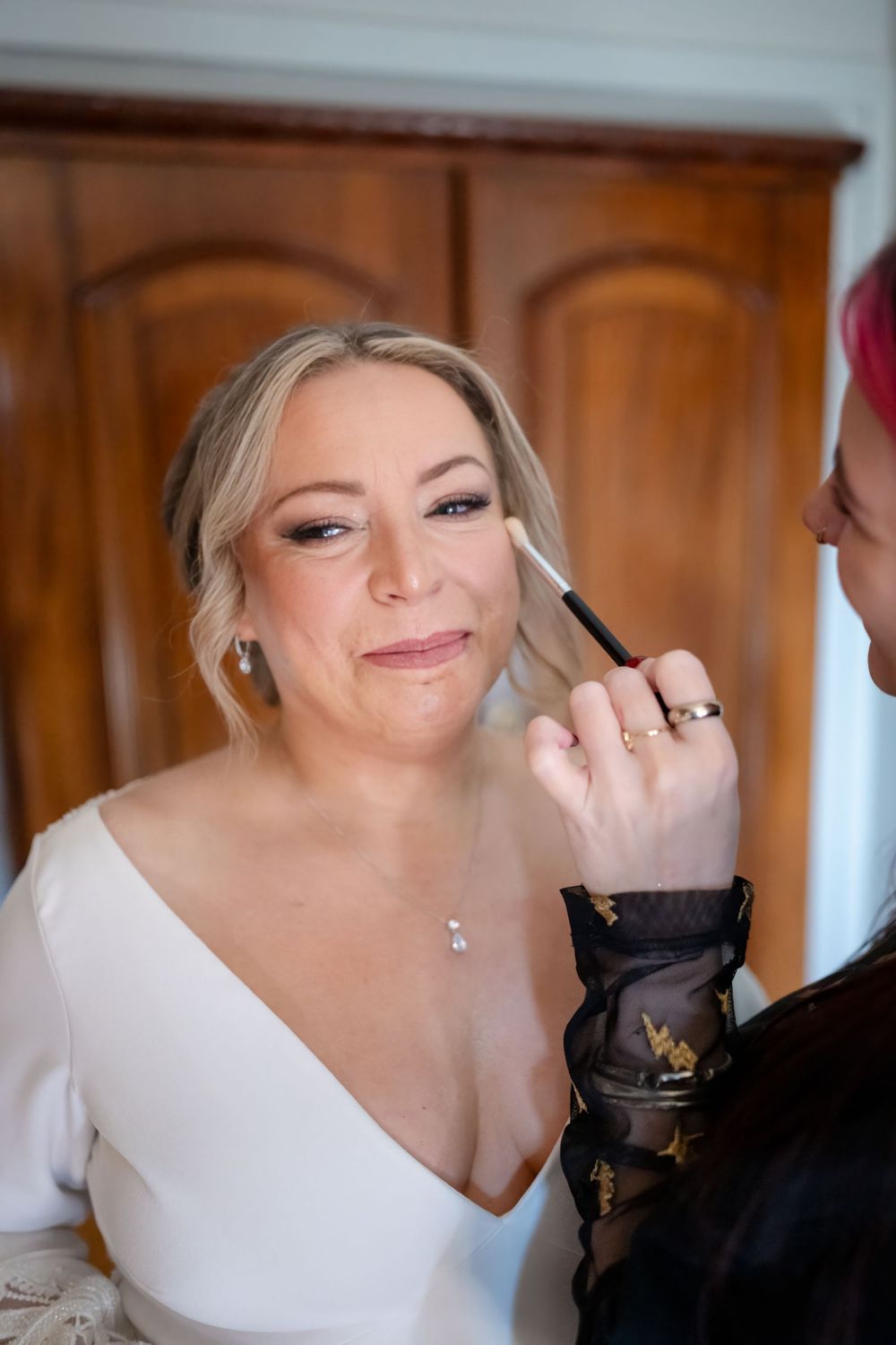 Makeup artist applying cosmetics during wedding preparation.