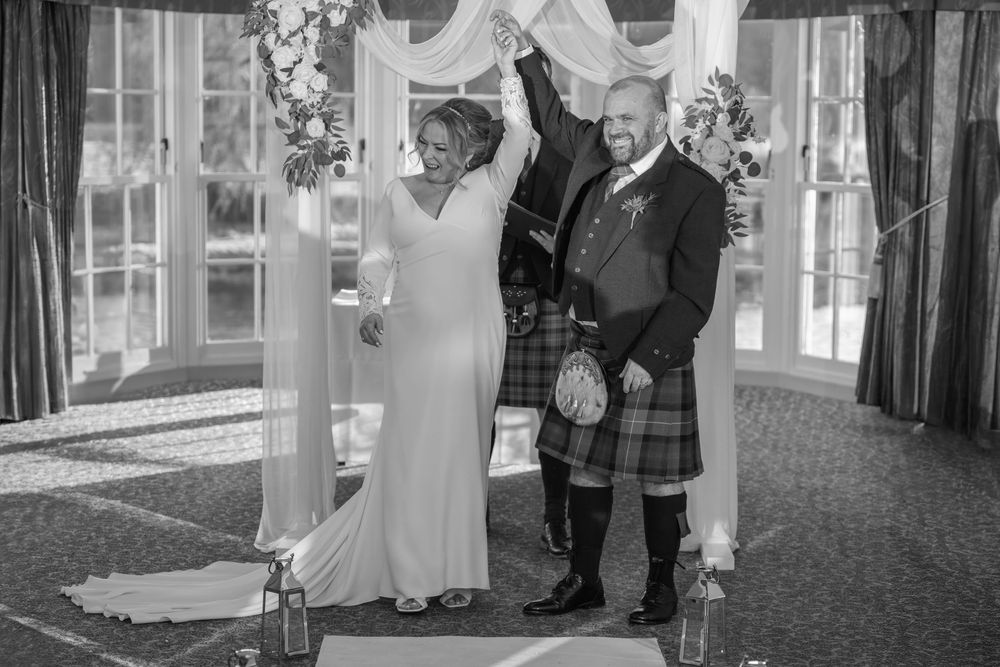 Wedding ceremony in an elegant indoor venue with white decor and natural lighting.