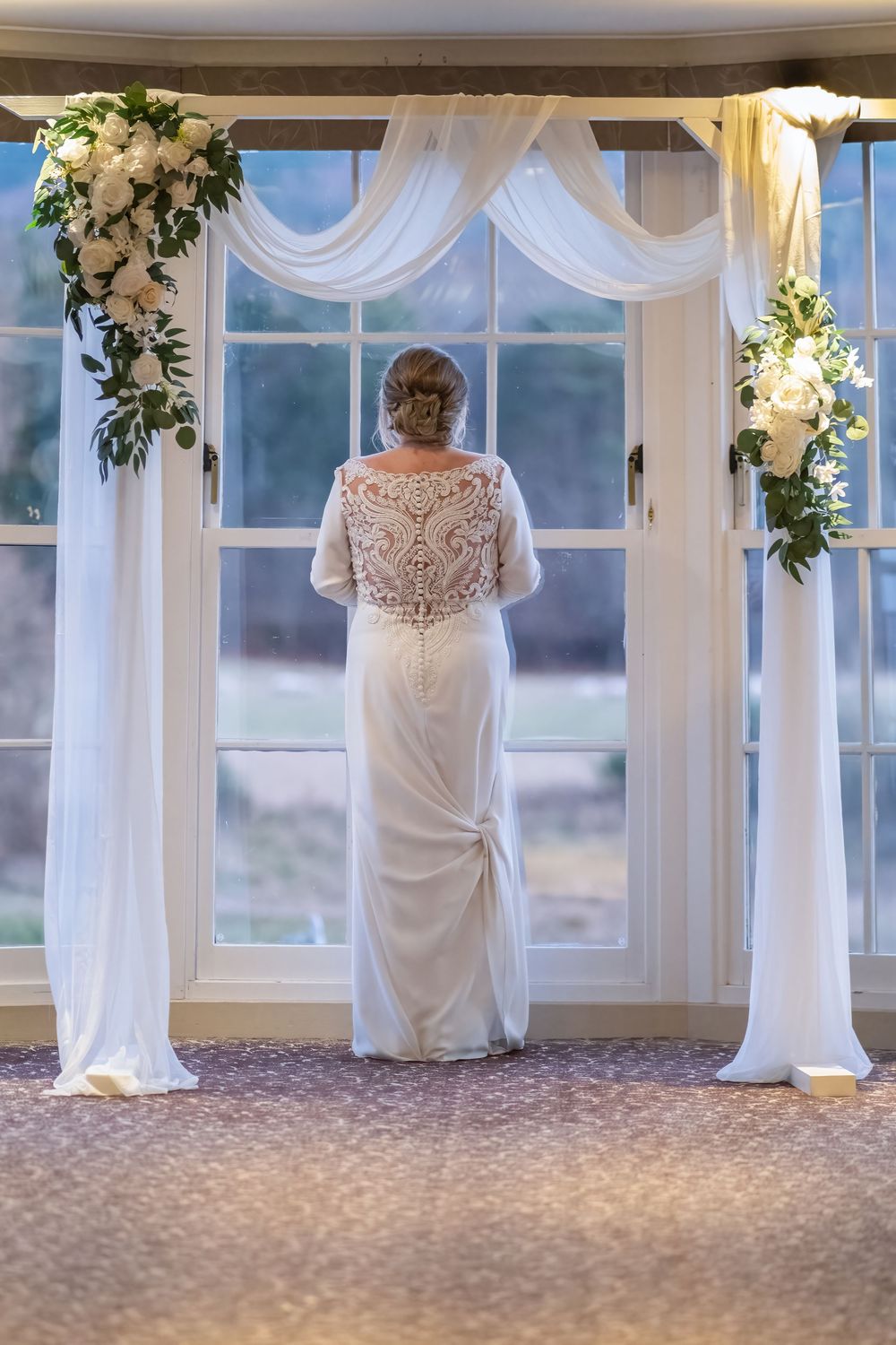White wedding dresses displayed in sequence against window-lit venue backdrop.