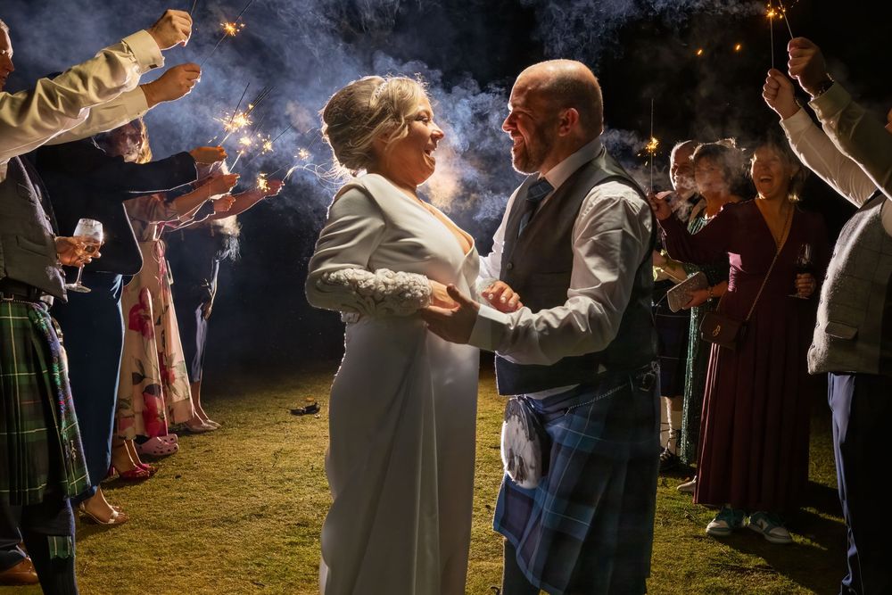 Wedding guests holding sparklers creating a magical nighttime atmosphere.