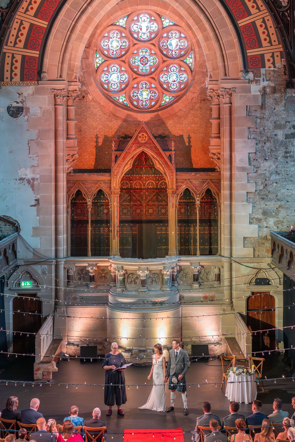 Wedding reception in historic church with Gothic architecture and dramatic red lighting.