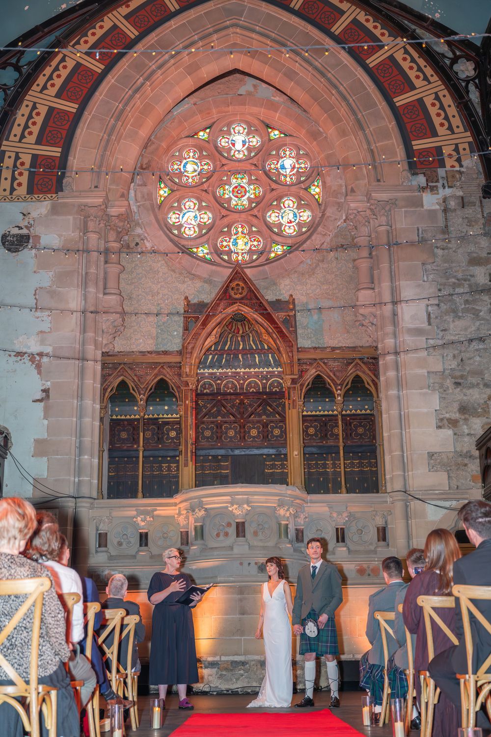 Wedding celebration in Gothic cathedral with stained glass windows and ambient lighting.