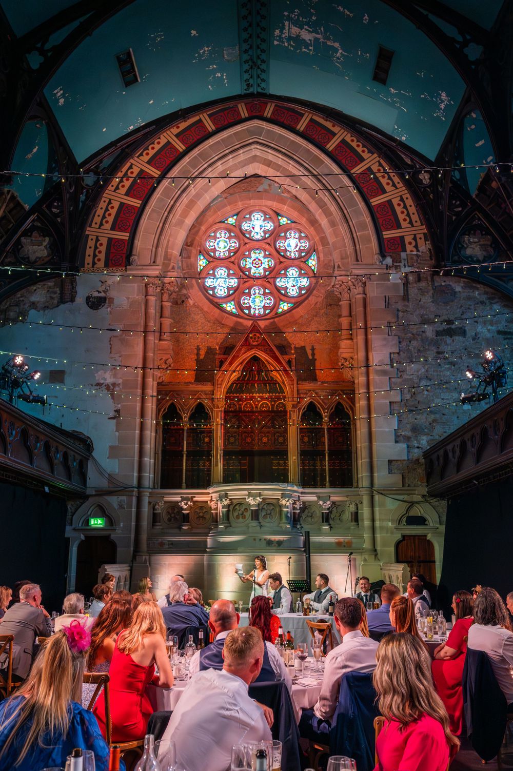 Wedding reception in a historic church venue with stained glass windows and warm lighting.