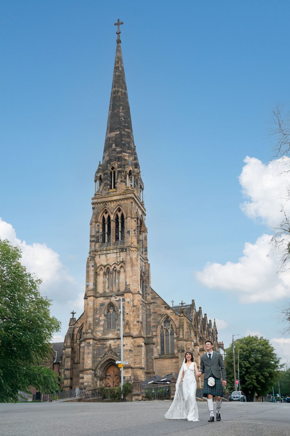 Gothic stone church exterior with tall spire against blue sky.