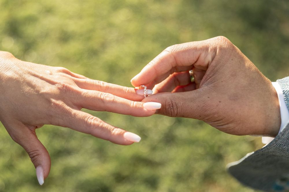 Close-up view of hands in a sequence showing rock paper scissors game moves against a blurred outdoor background.