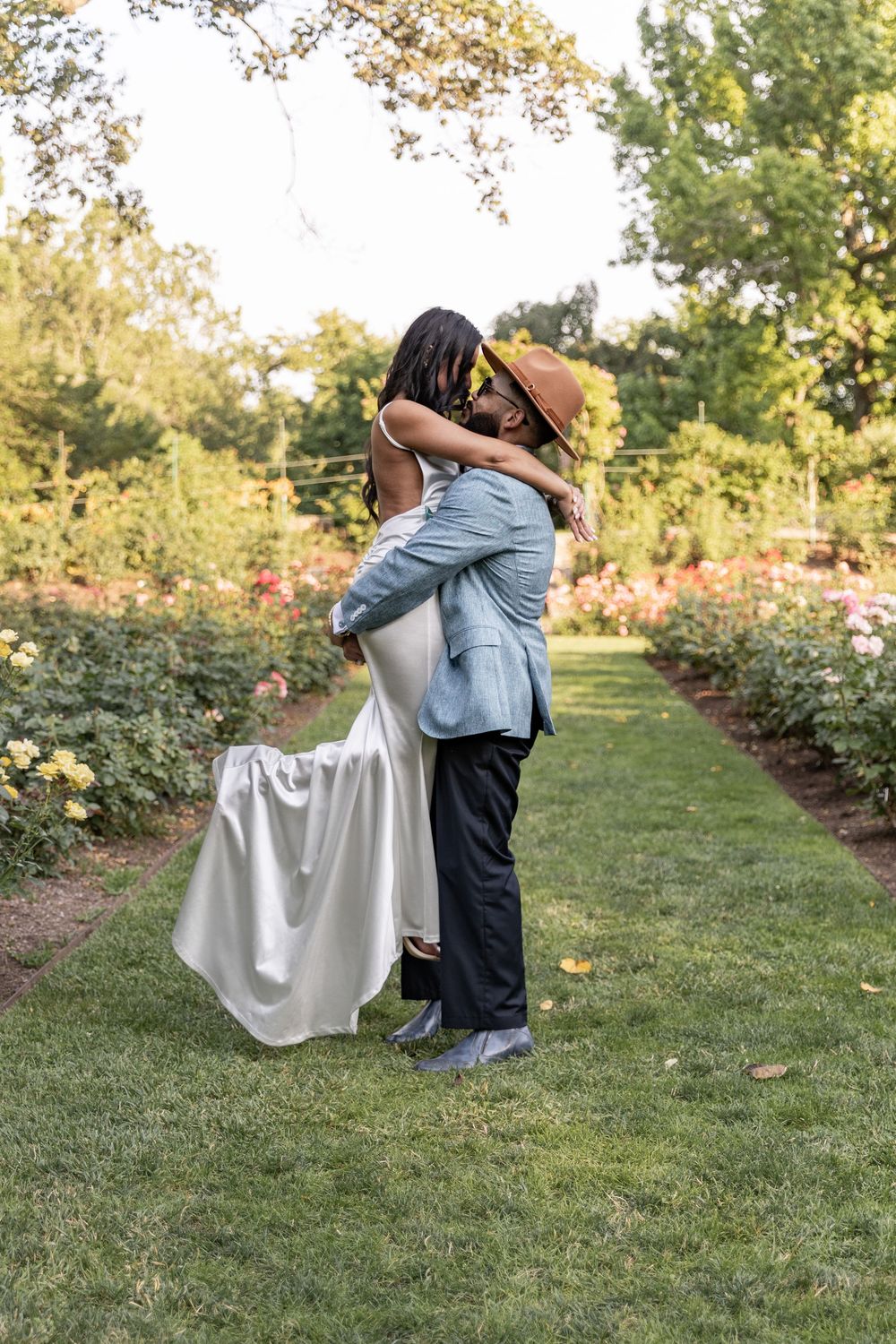 A romantic proposal scene unfolds in a garden with blooming roses as a couple shares a tender moment on a summer day.