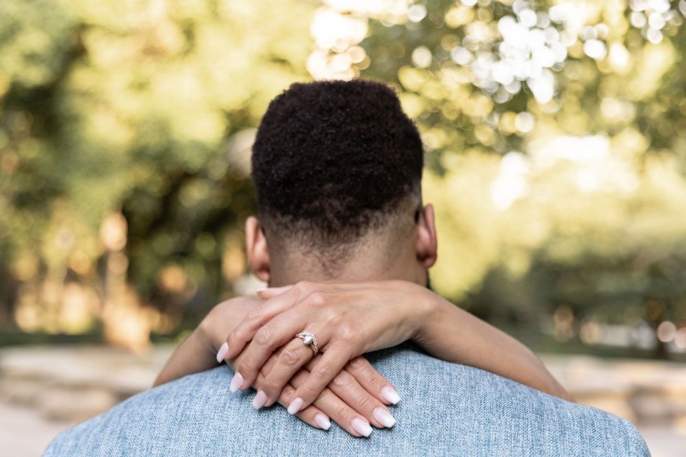 A close-up sequence of hands resting on shoulders against a sunlit outdoor background.