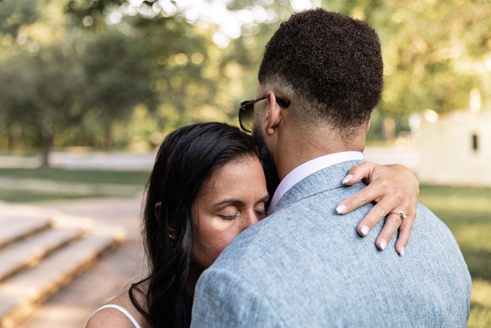 Romantic couple embraces in a sunlit park setting during an intimate outdoor photo session.