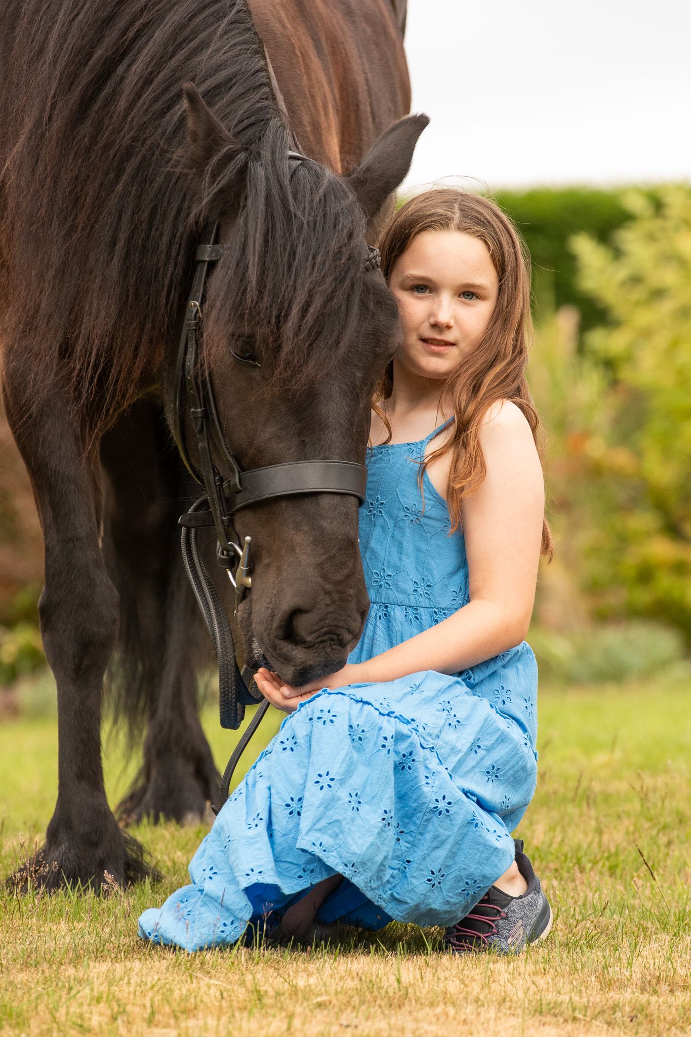 Young equestrian poses with palomino pony in a series of natural outdoor portraits showing their special bond.
