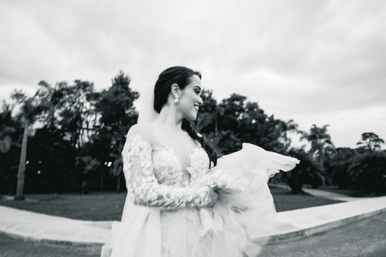 Bride's white dress flows dramatically in the wind during outdoor photo session.