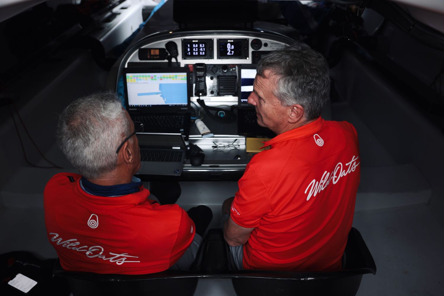 Crew members monitor navigation equipment in dark control room.