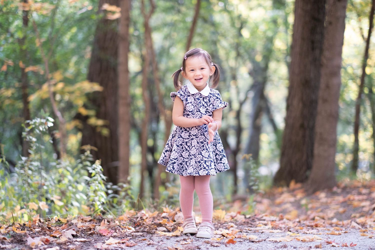 A series of outdoor portraits in a wooded setting with autumn leaves scattered on the ground.