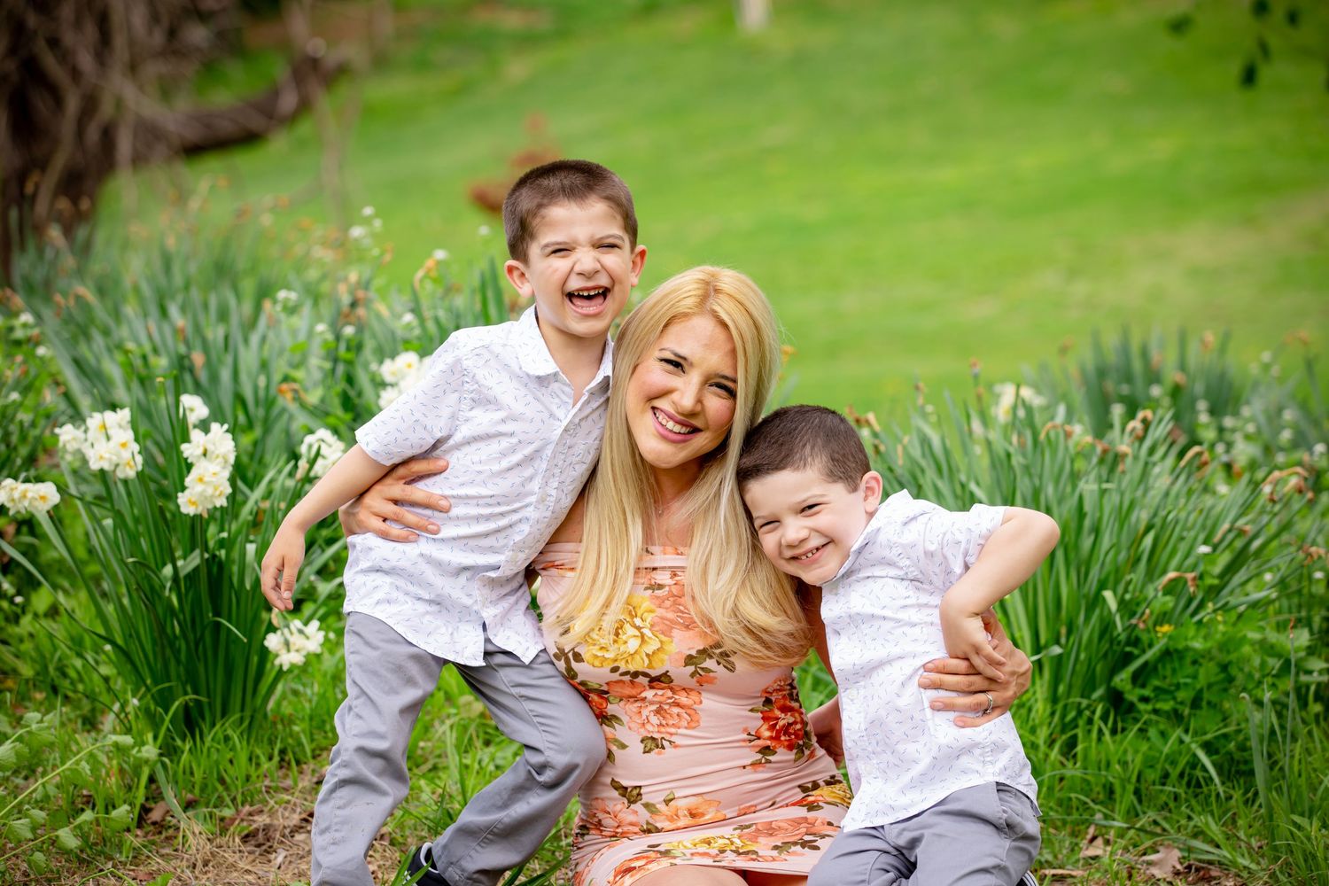 A joyful outdoor family portrait in a spring garden with blooming daffodils and lush green grass.