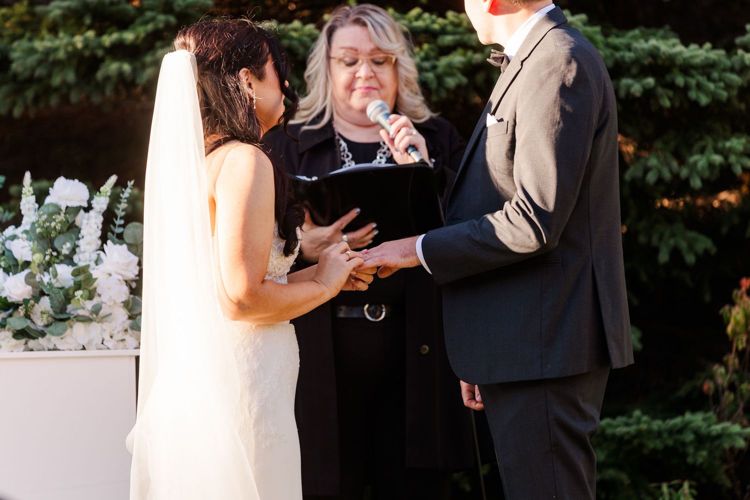 A couple shares an intimate moment during their wedding ceremony in a lush outdoor garden setting.