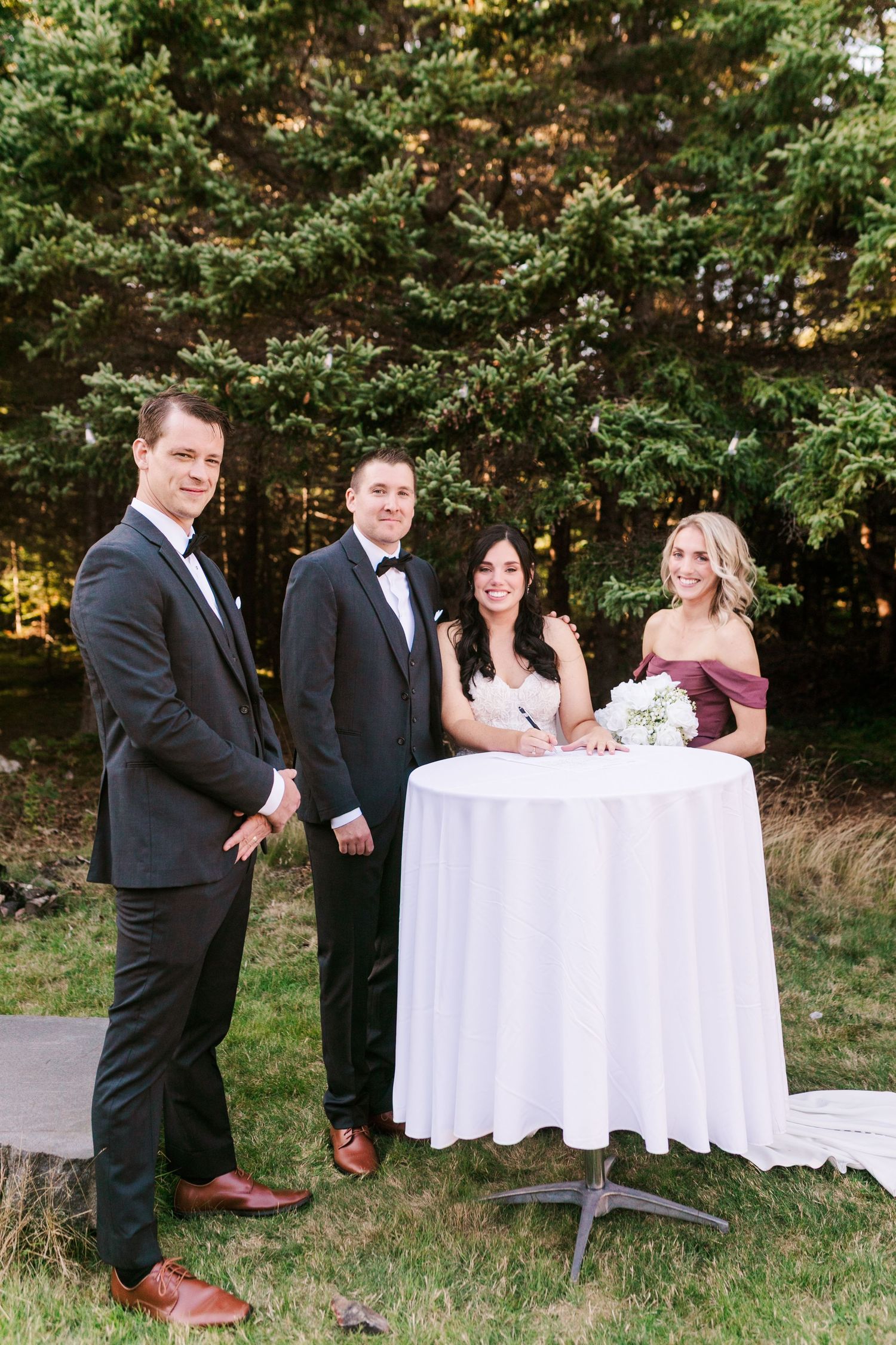 A series of four candid moments showing wedding party members laughing together at a white-clothed table outdoors.